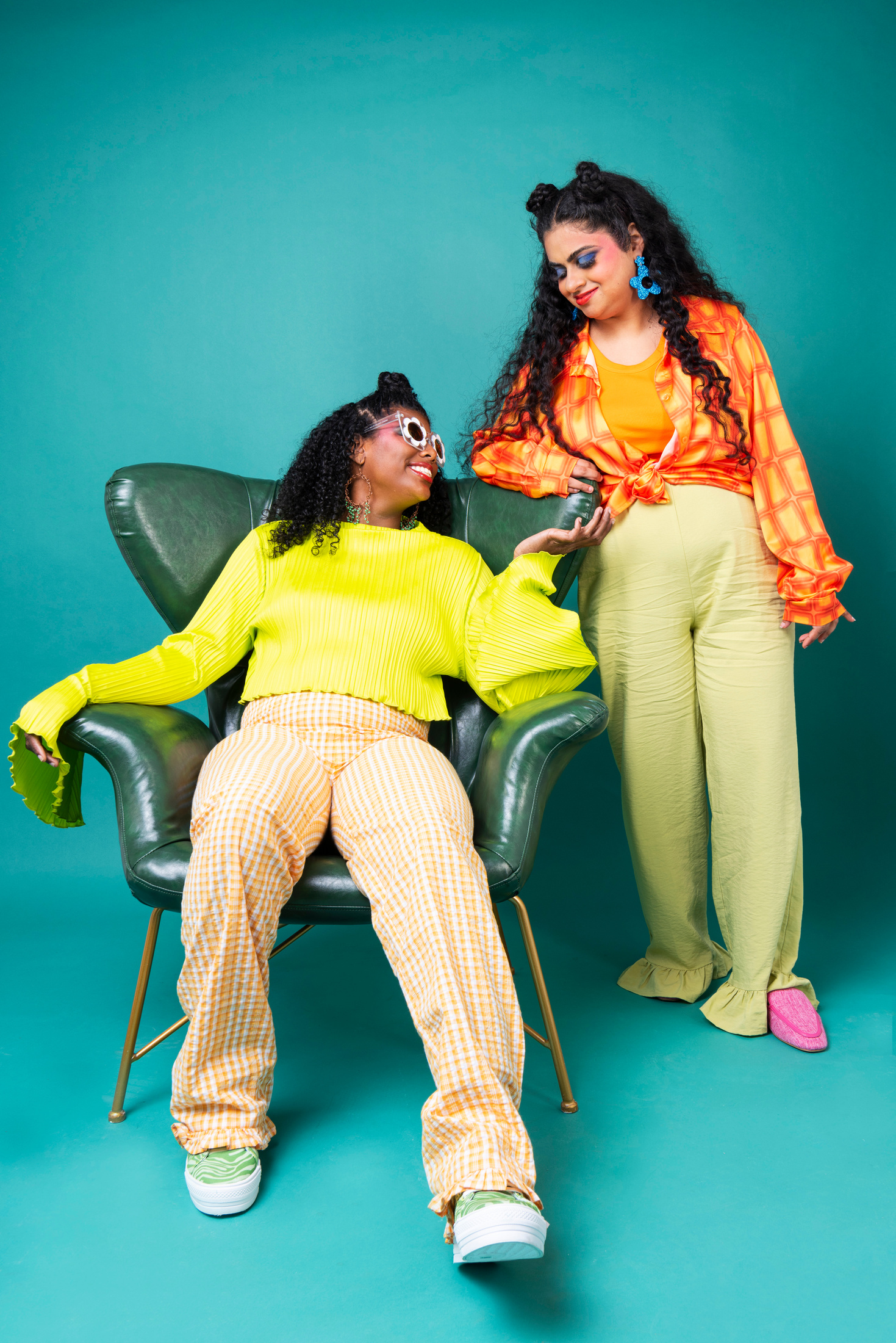 a photo of two people in bright clothing sitting on a green chair